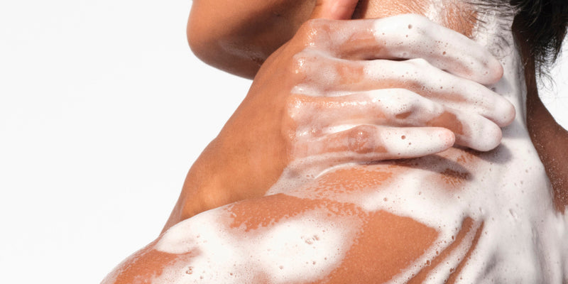 A person covered in white body wash suds, illustrating the best body wash for sensitive skin and ingredients that moisturize skin