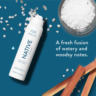 Native deodorant spray with text saying "A fresh fusion of watery woodsy notes", styled with grains of sea salt