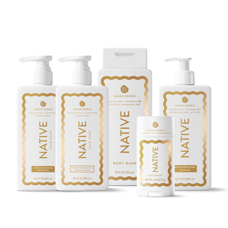 A set of Native Holy Care personal care products in a clean white studio setting, including body wash, moisturizer, body wash pump bottles, a deodorant stick, and a body wash box, all with white packaging and gold labels.