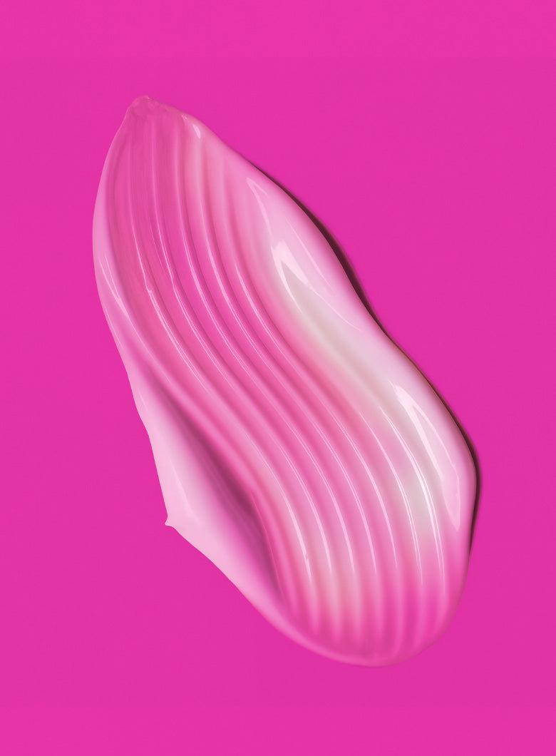 A glossy, wavy smear of pink cosmetic cream or gel on a solid bright pink background.