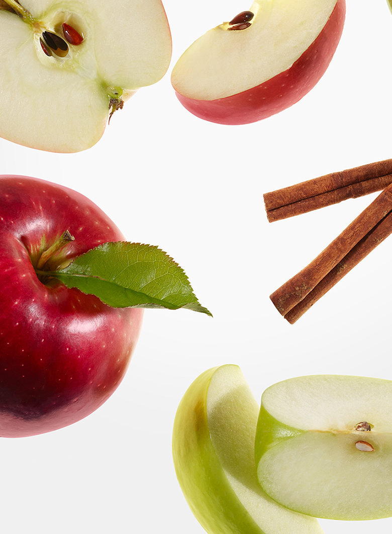Fresh red and green apples shown sliced and whole, with cinnamon sticks on a clean white background.