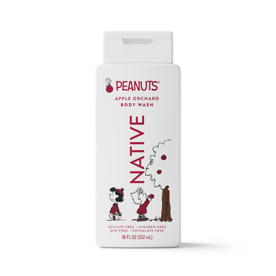 A white rectangular bottle of Peanuts Apple Orchard Body Wash with a flip-top cap. The label features red text reading 'PEANUTS' and 'BODY WASH' with 'NATIVE' printed vertically in red.