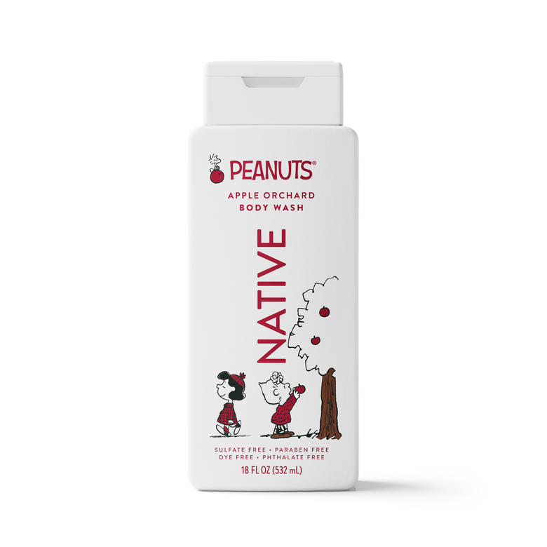 A white rectangular bottle of Peanuts Apple Orchard Body Wash with a flip-top cap. The label features red text reading 'PEANUTS' and 'BODY WASH' with 'NATIVE' printed vertically in red.