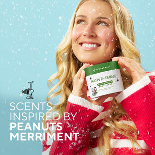 Woman with Native x Peanuts Body Scrub, highlighting festive Peanuts-inspired scents.