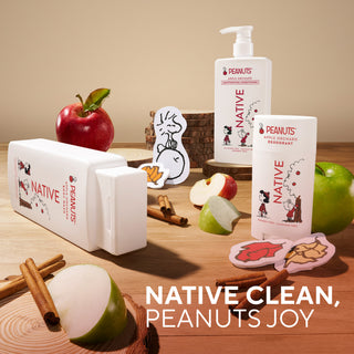 Three Native Clean products in white packaging arranged on a wooden surface with apples, cinnamon sticks, and autumn-themed stickers. Visible text includes 'NATIVE CLEAN, PEANUTS JOY' and product labels such as 'Apple Cinnamon Deodorant' and 'Peanuts Joy'.