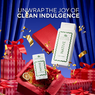 Native body wash and body butter products floating among red gift boxes and gold confetti, with blue draped curtains in the background and the headline 'UNWRAP THE JOY OF CLEAN INDULGENCE'.