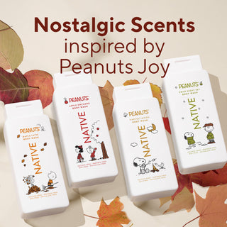 Four white Native Peanuts body wash bottles arranged on a beige background with autumn leaves. Large text at the top reads 'Nostalgic Scents inspired by Peanuts Joy.