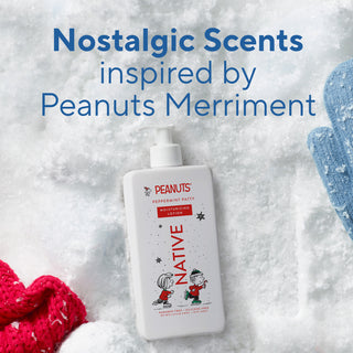 A bottle of Peanuts-themed moisturizing lotion labeled 'Native Peppermint Party' is placed on a snowy background with red and blue knit gloves and large blue text reading 'Nostalgic Scents inspired by Peanuts Merriment.'.
