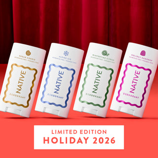 Four Native brand deodorant tubes arranged in a row against a red curtain background, with a red lower surface and a white label at the bottom reading 'LIMITED EDITION HOLIDAY 2026.' The tubes are white with decorative gold, blue, green, and pink labels, and the scents shown are Sugar Cookie, Alpine Air, Minting Citrus, and Holiday Gumdrop.
