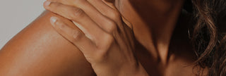 Close-up of a person's hand on their shoulder with a blurred background